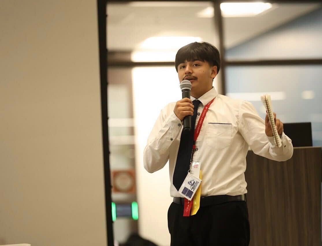 An LIT student speaking into a microphone while holding his notes